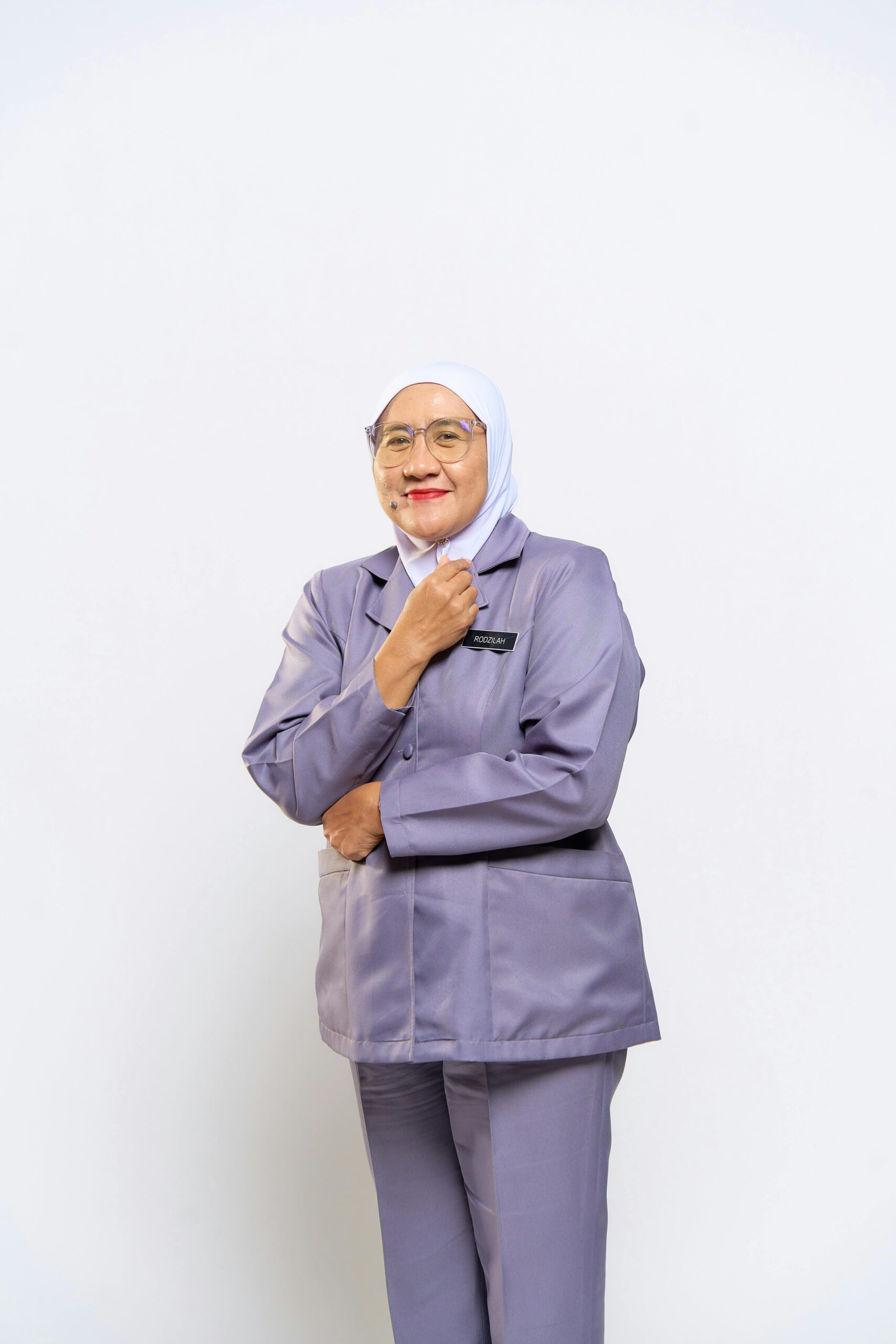 Elderly woman in formal attire, smiling confidently while posing indoors against a white background.